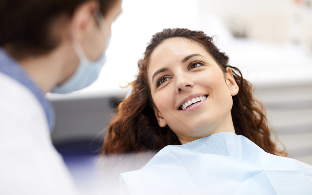 Smiling patient in chair talking with her dentist