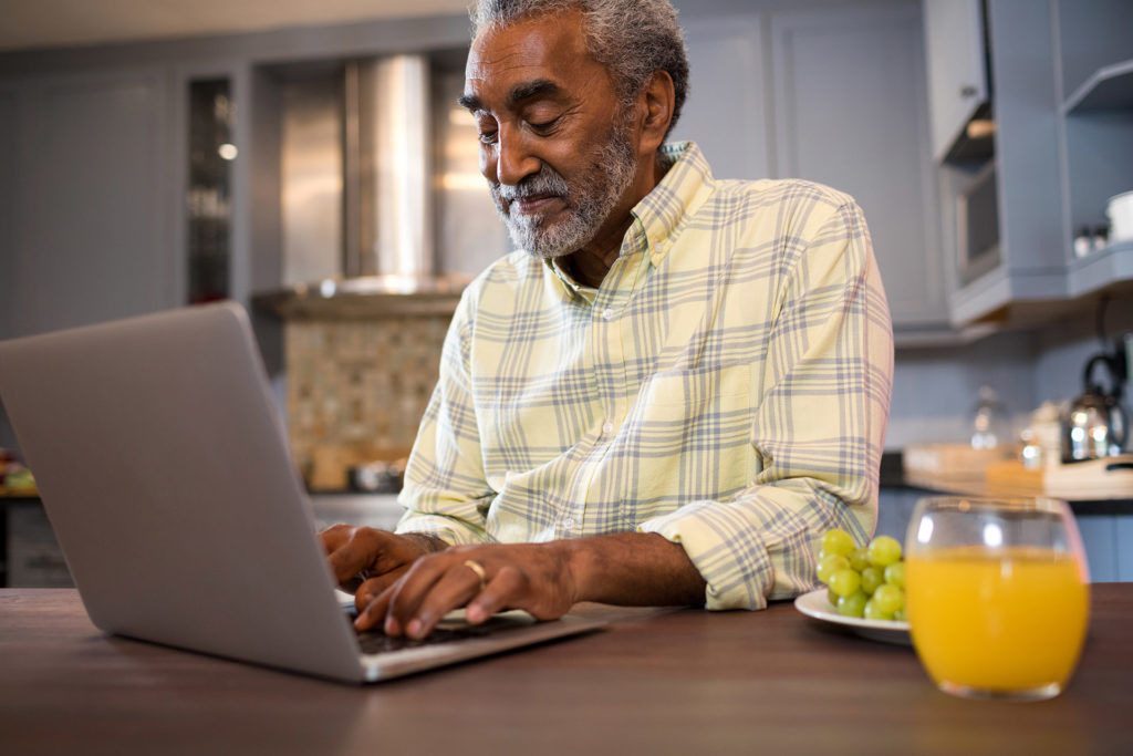 Senior man using laptop at home to find a local dentist