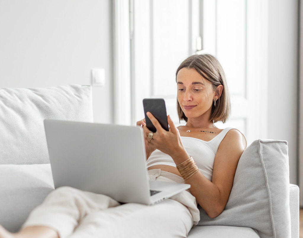 Woman on her phone and laptop looking at the top site ranks listed because of practice SEO and impressed by site speeds. 